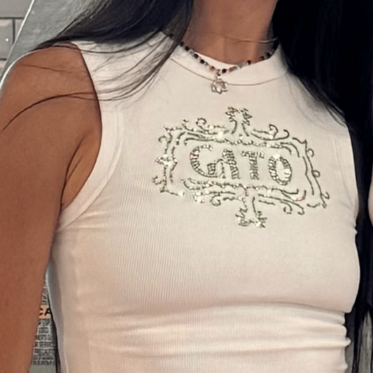 Person wearing a white sleeveless top with 'Gato' print and white pants.