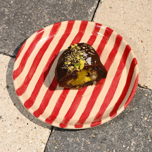 Chocolate-covered date on a red and white striped paper plate on a concrete surface